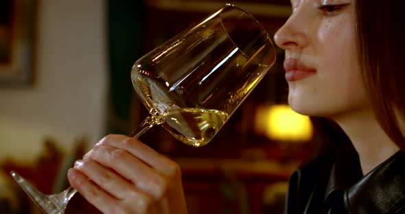 Young Pretty Woman Is Sipping White Wine From Glass in Restaurant alt
