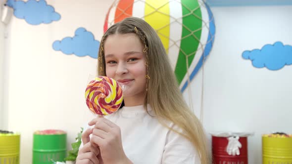 Smiling Beautiful Little Girl with Colored Lollipops on a Stick in the Pastry Shop alt
