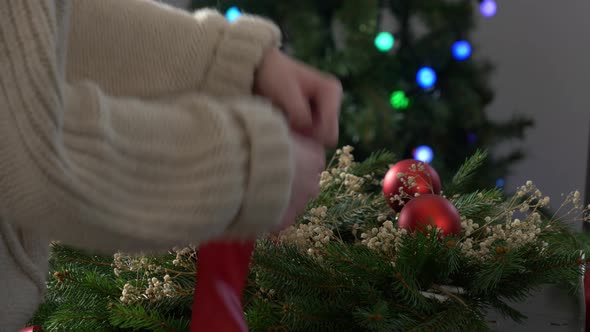 Female decorates the Christmas wreath herself on table at home alt
