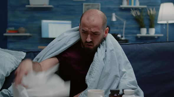 Close Up of Sick Man Blowing Runny Nose with Tissues alt