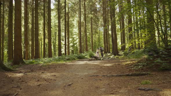 Two Mountain Bikers Cycling At Speed Through Forest alt