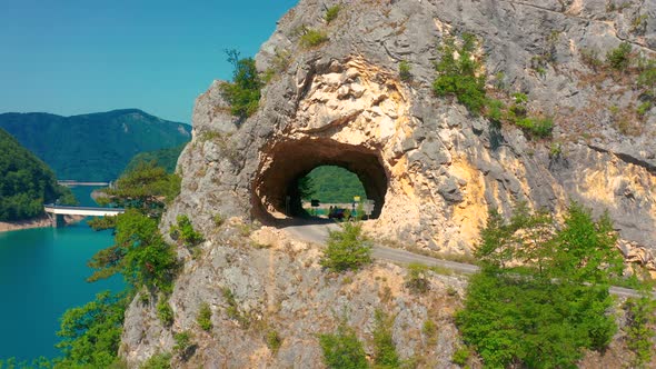 Tourists Stand in the Tunnel at Piva Lake in National Park Dormitor of Montenegro at Summer alt