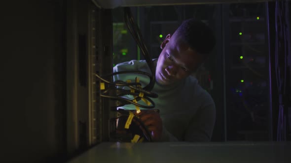 African american male computer technician using smartphone working in business server room alt
