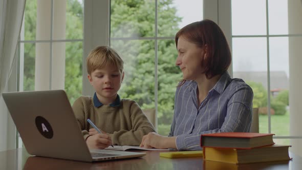 Young Mother Making Online Homework with School Kid at Home alt