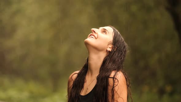 Slow Motion of a Young Beautiful Woman Closes Her Eyes with Pleasure While Enjoying the Summer Rain