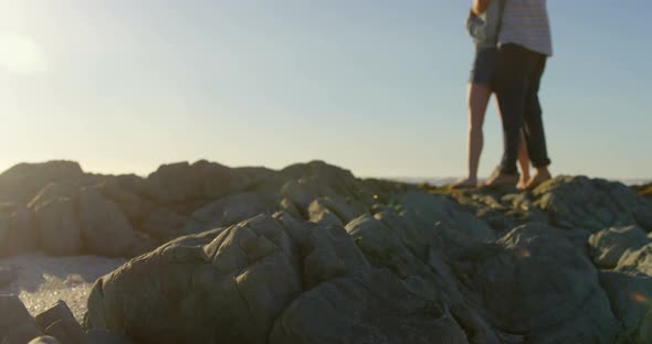 Romantic young couple embracing on rock at beach 4k alt