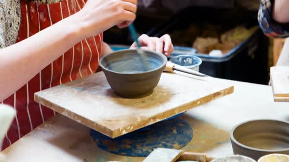 Female artist painting on earthenware bowl alt