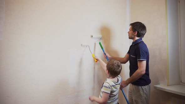 Dad and son paint beige wallpaper with white paint with a large and small roller alt
