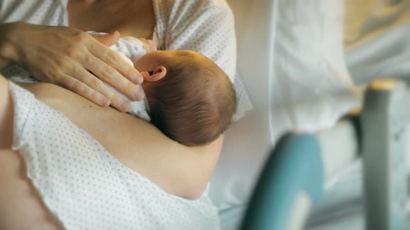 Mother breastfeeds and caresses newborn baby alt