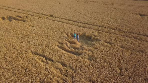 Two little girls joyfully jump and dance in a wheat field. top view, shooting from a copter.