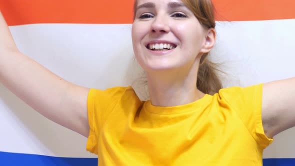 Netherlands Young Woman Celebrating while Holding the Flag of Netherlands alt
