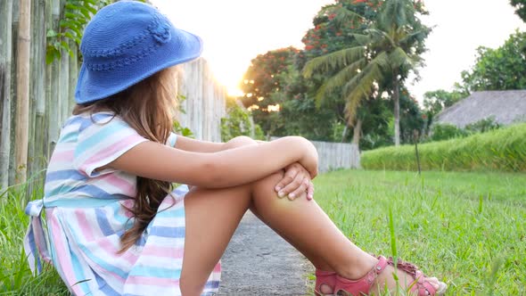 Happy Little Girl Sitting on the Grass and Playing in Summer Garden alt