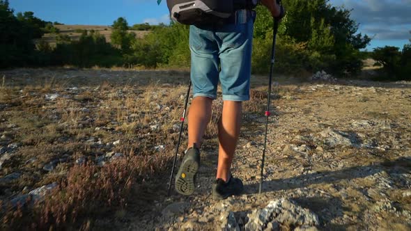 Back View of Male Hiker is Walking Along Rocky Area and Smiling on Summer Day Spbd