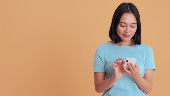 Positive woman in blue t-shirt typing by phone alt