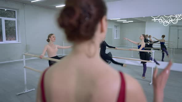 Back View Blurred Choreographer Clapping Talking As Young Slim Ballerinas Moving Legs Up Smiling at alt