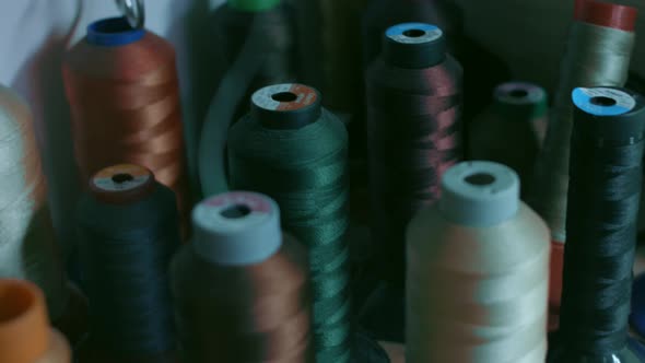 Spools of Thread for Sewing Shoes in Dark Colors Stand on a Shelf alt