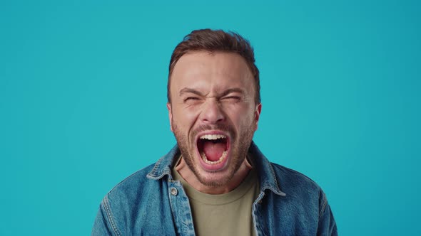 Angry Young Man Shouting Against Blue Background