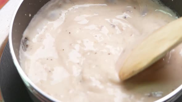 Homemade mushroom carbonara sauce in a pot on the electric stove in the kitchen. alt