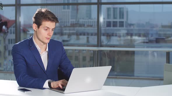 Portrait of Young Attractive Businessman Working at a Desk, Use Laptop in the Office.