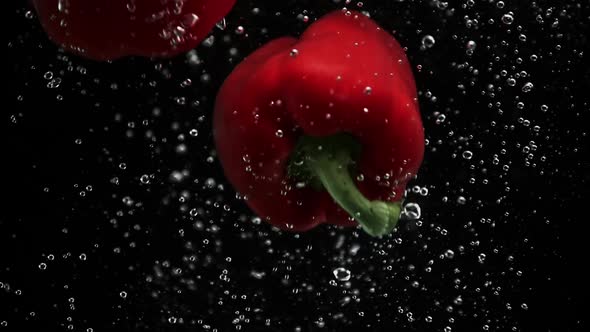 Ripe Bell Peppers Falling Into Water Black Background alt