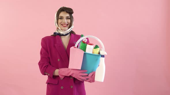 A Woman with a Scarf on Her Head Holds a Bucket with Tools for Cleaning