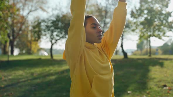 Girl Doing Breathing Exercises at the City Park in the Autumn Morning alt