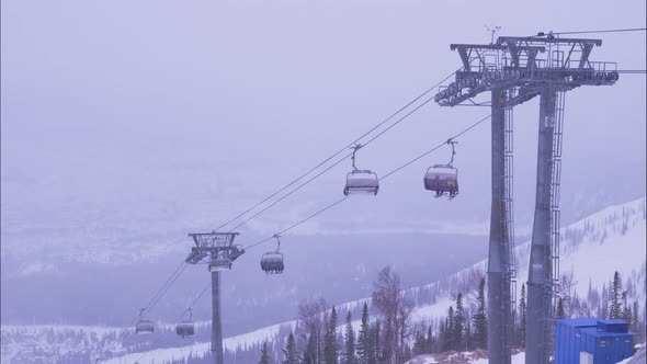 People Ride Poma Lift Over Slope While Heavy Mist Coming alt