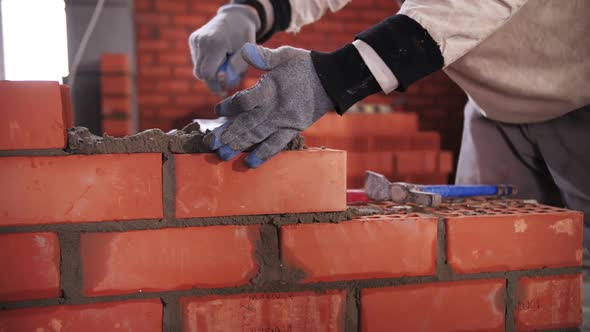 builder lays red brick close-up alt