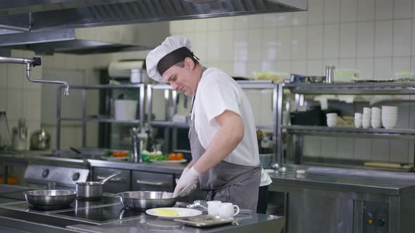 Portrait of Male Cook in Uniform Cleaning Kitchenware in Restaurant Kitchen Indoors alt
