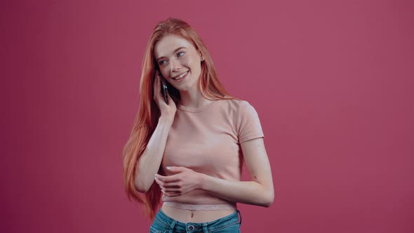Happy Redhaired Young Woman Talking on the Phone Excited with Her Mouth to Her Mouth alt