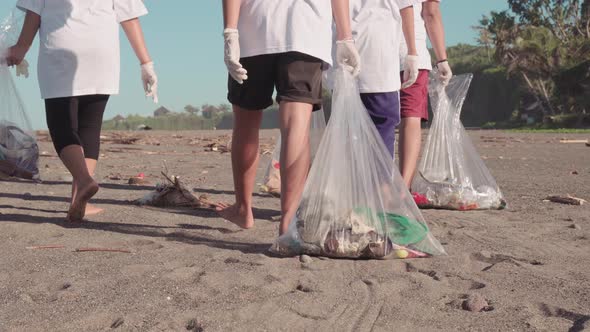 Unrecognizable Legs On Beach With Trash Bags alt