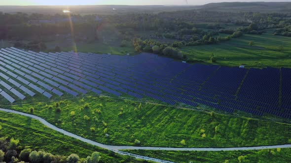 Aerial view on Solar Power Station in Green Field near River at Sunny Day. alt