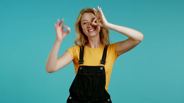 Cute Woman Showing Okay Sign Over Blue Background. Positive Young Girl Smiles To Camera. Winner alt