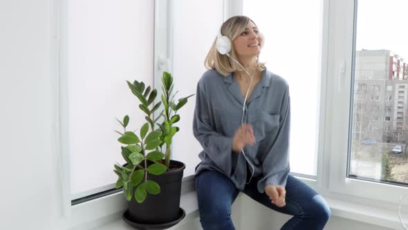 Portrait of cheerful european woman in headphones listening to music