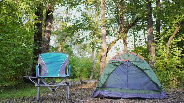 A Small Tent and a Chair for Rest Stand in the Forest