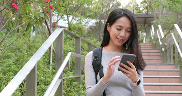 Woman checking on mobile phone at outdoor alt