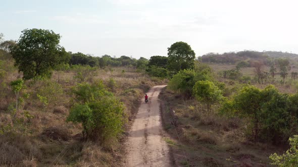 Aerial shot following a scooter driving in the countryside. alt