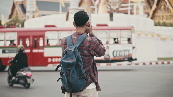 An attractive handsome tourist Asian man uses a film camera to take a photo.