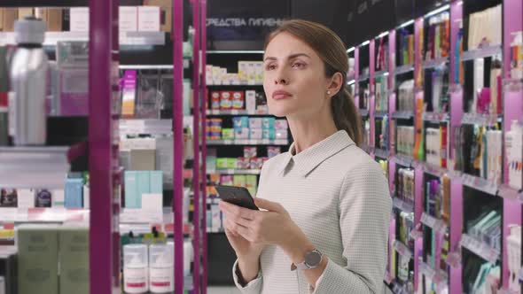 Beautiful Woman With Smartphone In Cosmetics Store alt