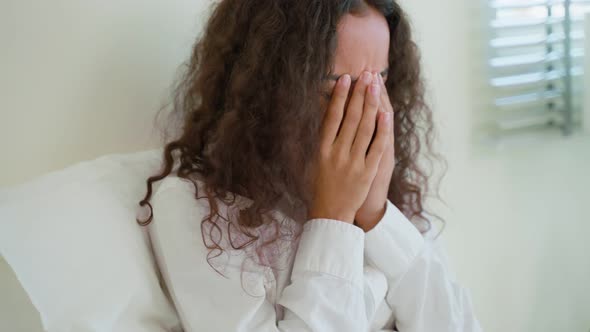 Beautiful depression Latino girl crying in tears sit on bed in bedroom. alt