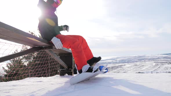 A Young Woman on a Snowboard on Top Mountain on a Ski Track alt