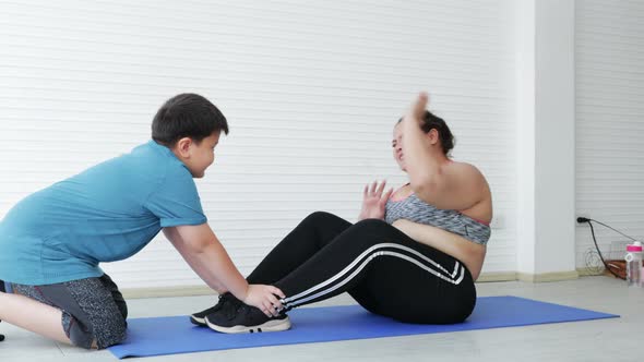 Overweight unhealthy woman doing sit-ups with her son for health care together