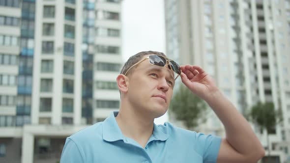 Portrait of a Young Attractive Man Against the Background of City Buildings