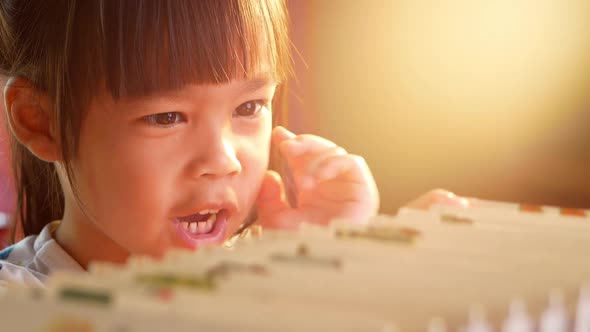 A little cute girl is choosing a book in the bookshelves at home. alt