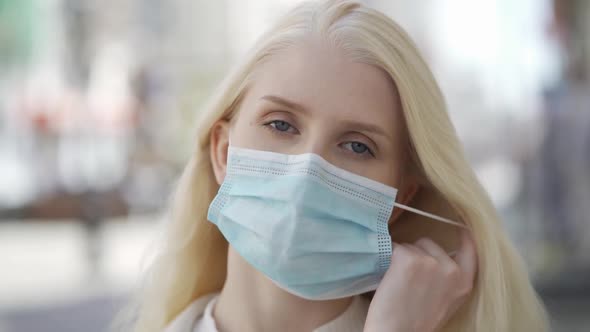 An Attractive Young Woman Takes Off Her Medical Mask and Smiles alt