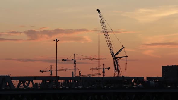 Construction Cranes at Work at Sunset