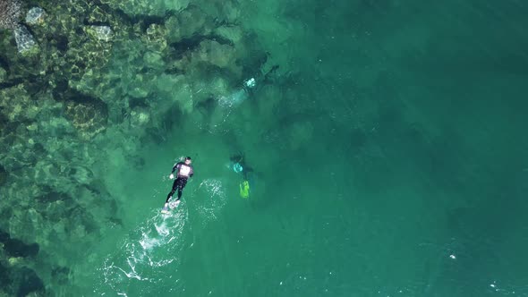 Unique view of a single person snorkeling above a group of scuba divers below the water in the ocean alt