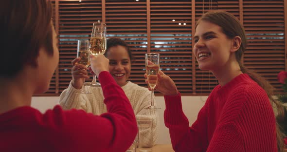 Group of young women clinking Champagne glasses celebrating Christmas at home