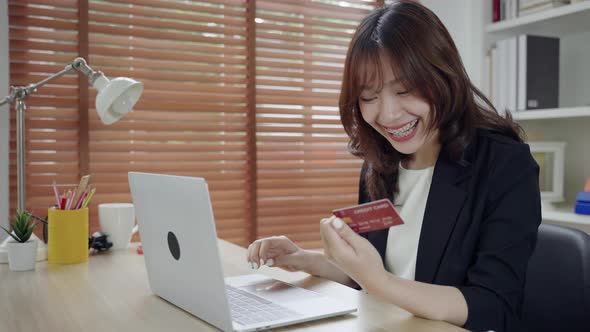 Beautiful Asian businesswoman using credit card (mock-up) to shopping online