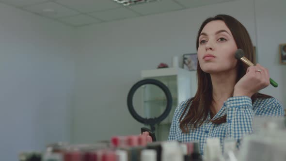 Young Attractive Woman Make Up Her Face in Front of the Mirror alt